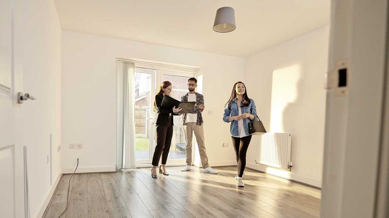 Jong koppel bezichtigt een woning met een makelaar.