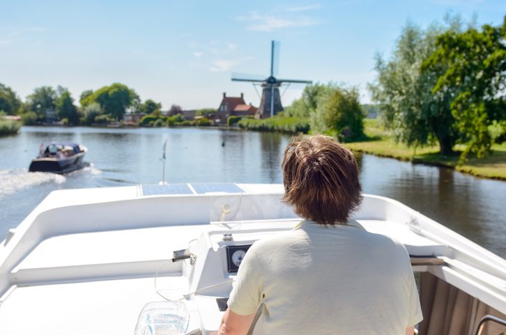 Man vaart met zijn boot en geniet van het weer.