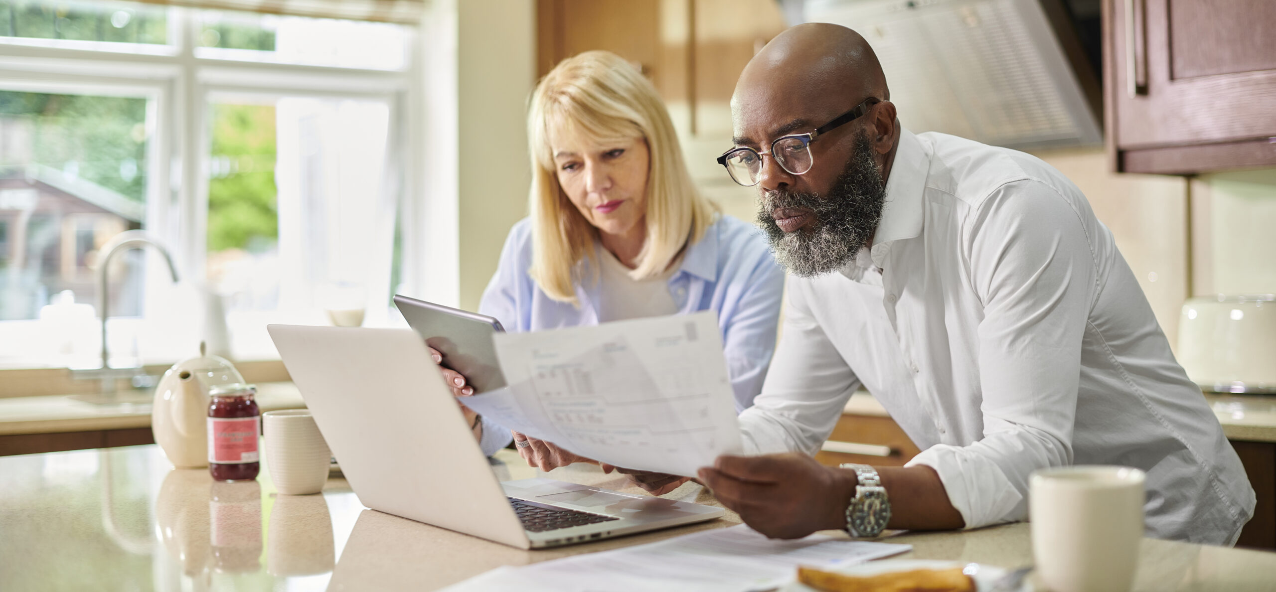 Stel balanceert de gezinsfinanciën in de keuken met hun laptop.