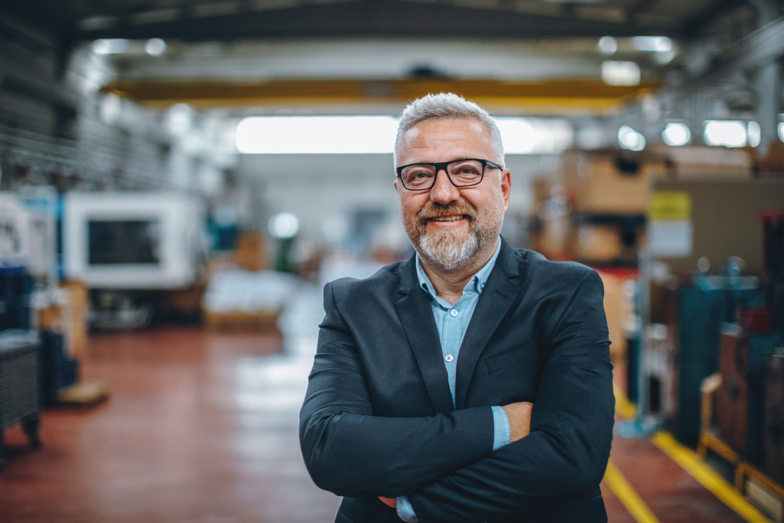 Portret van lachende senior manager of CEO in een industriële fabriek.