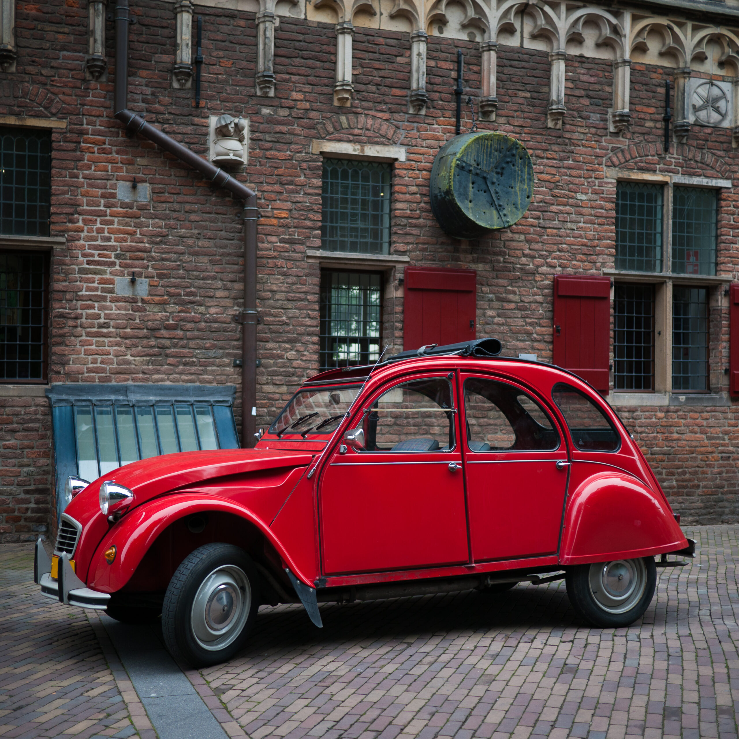 Oldtimer geparkeerd voor een oude fabriek.