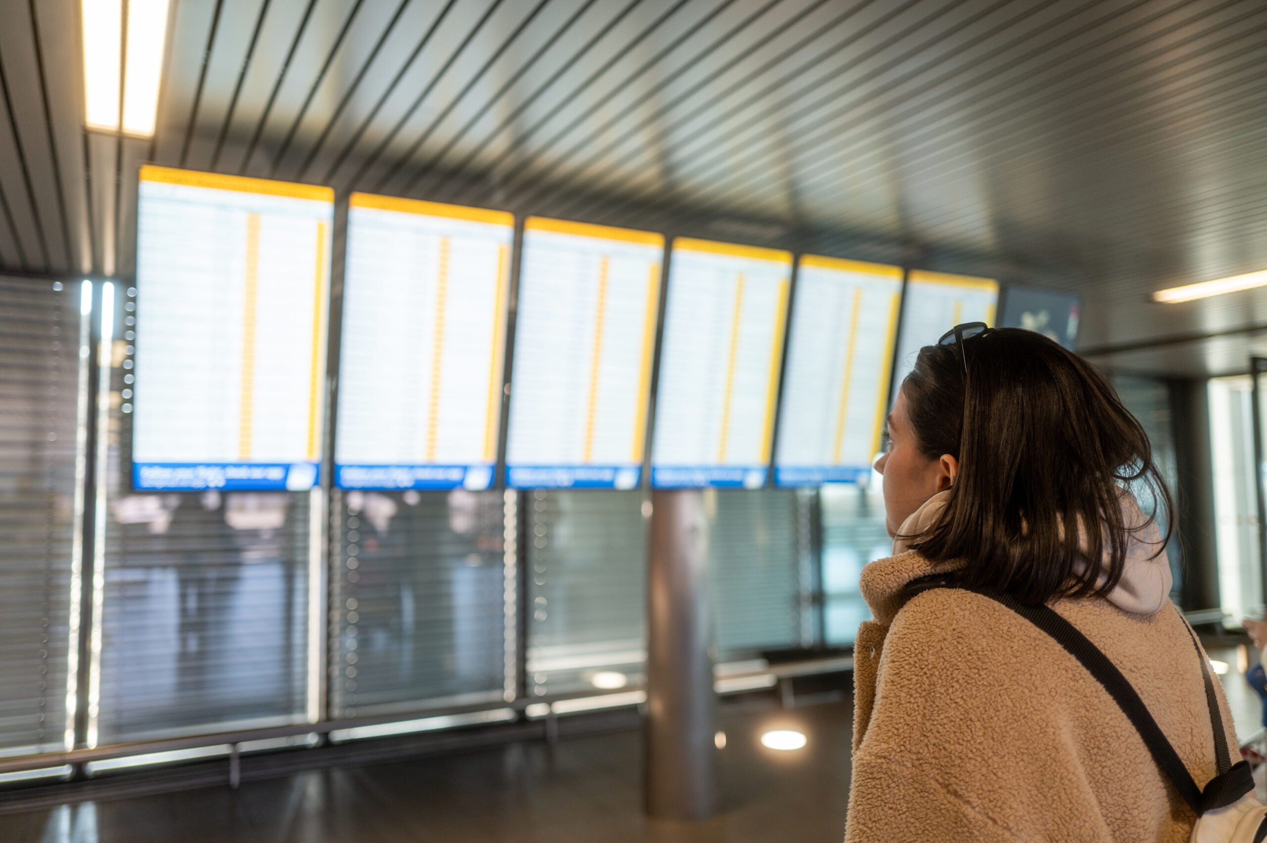 Vrouw kijkt naar een informatiebord op het vliegveld.