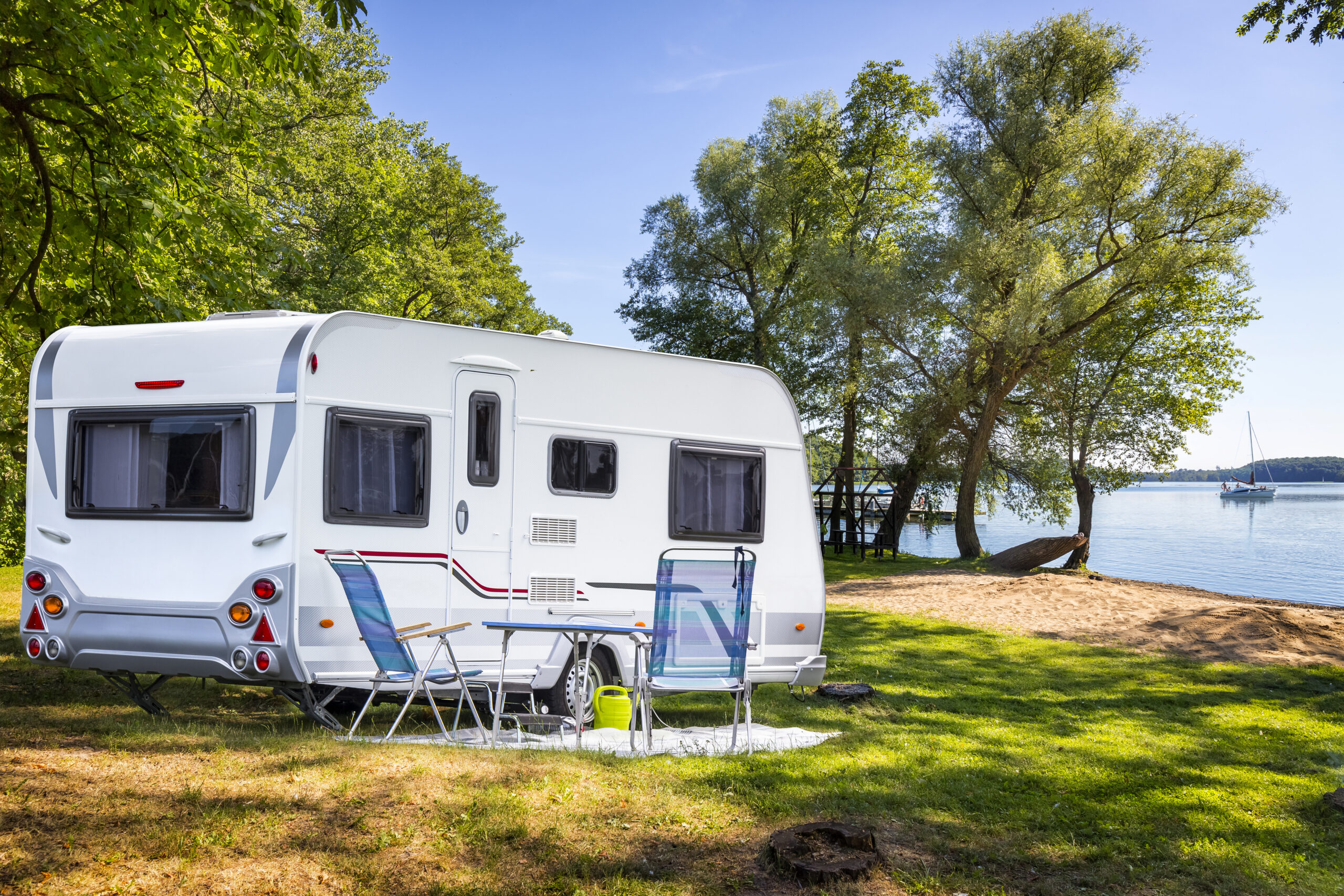 Caravan in de natuur aan een meer met een zithoek voor de caravan.