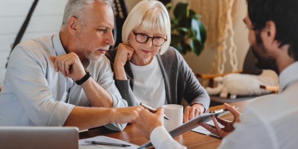 Financial advisor explaining paperwork to elderly retired couple front of desk