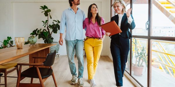 Real estate agent showing a new apartment and features of a good investment to a young couple. Woman and man buying a property in a rich area of the city.
